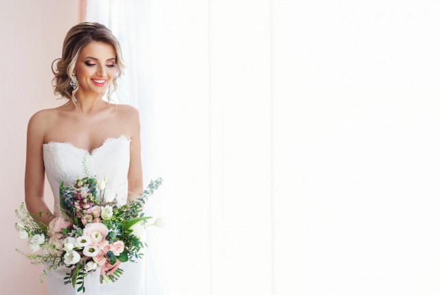 Woman wearing a wedding dress with a large bouquet — BAUNAT
