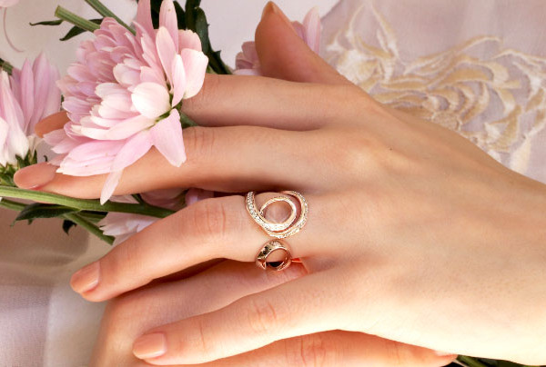 Hand with elegant wedding ring, holding pink flowers 