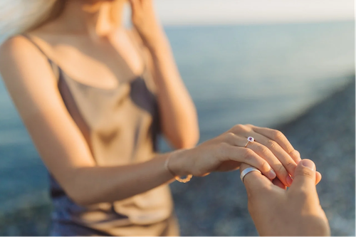 woman being proposed to on the beach with a stunning diamond engagement ring