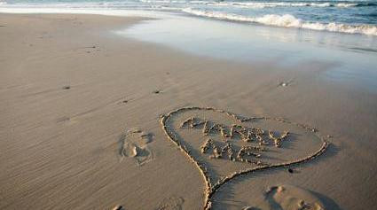a marriage proposal with the words ‘marry me’ inscribed in sand, creating a picturesque proposal setting 