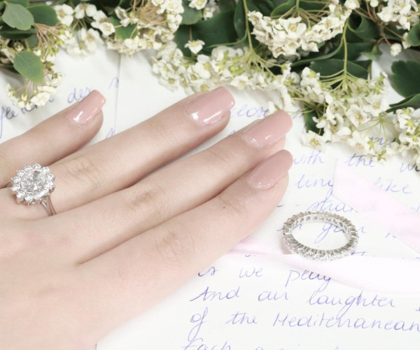 close-up of a woman's hand with a diamond ring and a wedding ring, featuring a traditional British engagement ring
