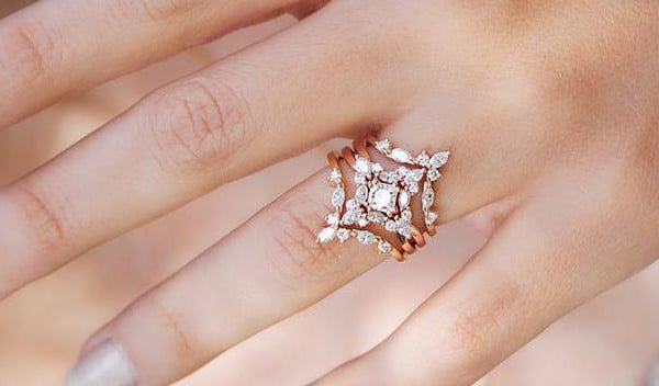 A close-up of a woman's hand elegantly holding a sparkling diamond ring, showcasing its brilliance and beauty