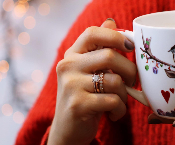 Person drinking tea and wearing differen types of diamond rings in rose gold