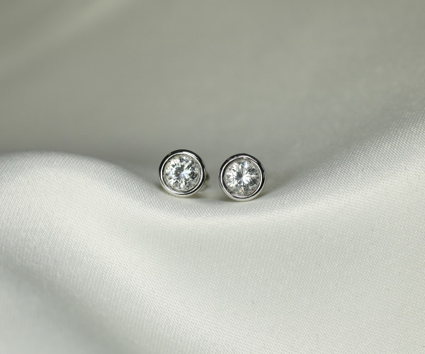 A pair of elegant silver stud earrings featuring sparkling diamonds, showcasing a refined and sophisticated design.