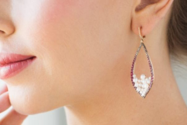 A woman displays stunning long earrings with a unique white and purple pattern, enhancing her overall appearance beautifully.