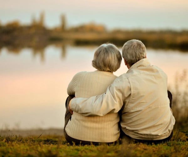 Old couple cuddling at the lakeside during sunset