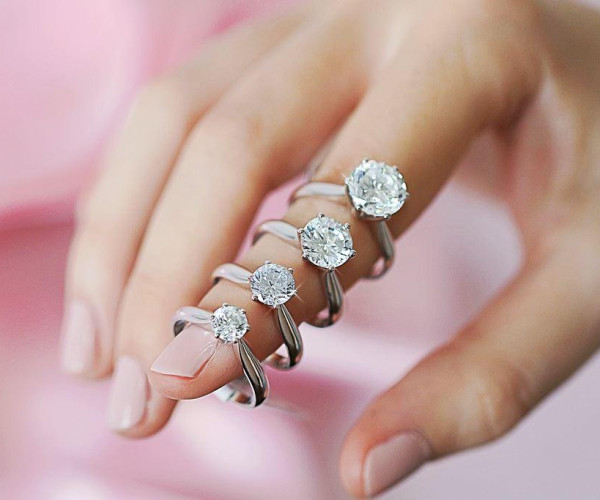 A woman's hand elegantly displays three distinct diamond rings, showcasing various styles and engagement ring sizes.