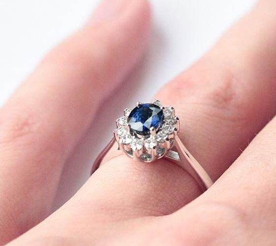 A close-up of a woman's hand displaying a beautiful blue sapphire ring, highlighting its elegance and diamond ring qualities