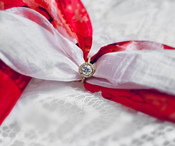 a wedding ring resting on a red and white ribbon, representing the bond of love and the promise of eternal commitment