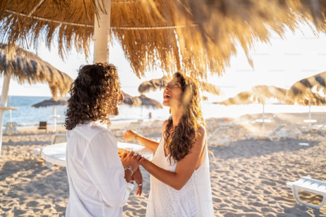 a couple enjoying their pre-moon holiday on the beach, with waves gently crashing nearby