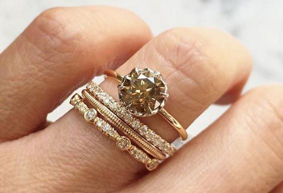Una donna che indossa tre anelli in oro giallo, ognuno dei quali riflette un design unico e il fascino degli anelli in oro giallo per donna.