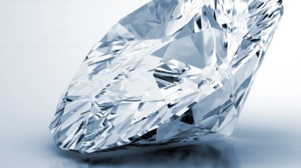 Un grande diamante trattato brilla su una superficie bianca, apparendo brillante anche se di qualità inferiore.