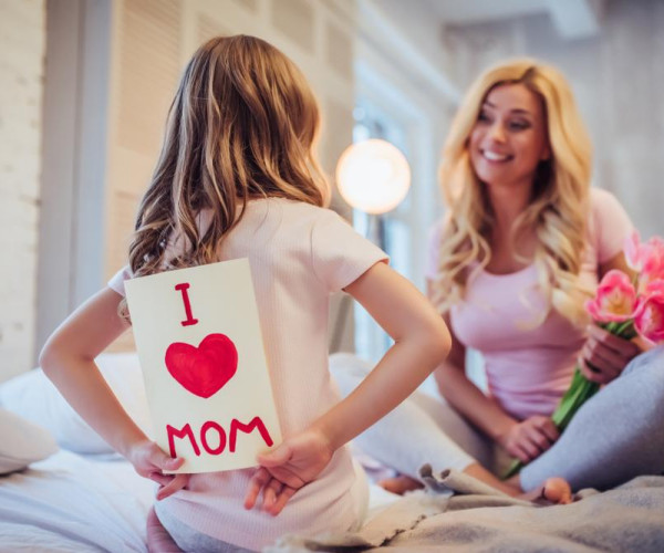 Un bambino sorprende la mamma con un disegno per la Festa della Mamma. Anche tu puoi regalarle un gioiello per la Festa della Mamma - BAUNAT