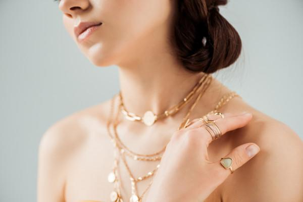 Una donna indossa diverse collane in oro rosso, creando un look sofisticato e di classe.