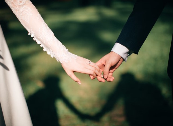 Primo piano di una coppia di sposi che si tengono per mano, mostrando il loro amore durante una tradizionale cerimonia di matrimonio inglese.