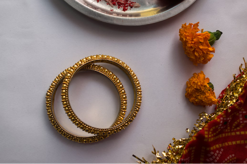 Una collezione di bracciali tradizionali in oro circondati da fiori vivaci su un tavolo splendidamente apparecchiato.