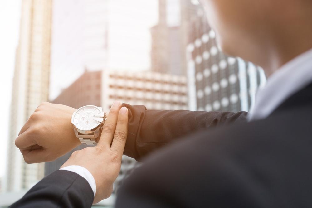 Jongeman in pak met een stijlvol horloge om de pols. Een geschikt afstudeercadeau, aldus BAUNAT.