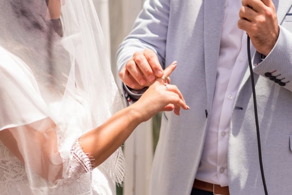 groom in jewish tradition shoving the bride’s diamond wedding ring on her right hand’s index finger