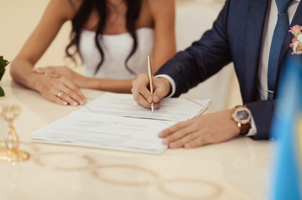 夫妇在结婚证书上签字。在国外结婚同样合法。 – BAUNAT