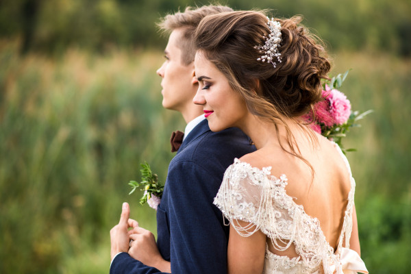 Bride and groom pose in front of a field, highlighting a traditional British engagement between two lovers