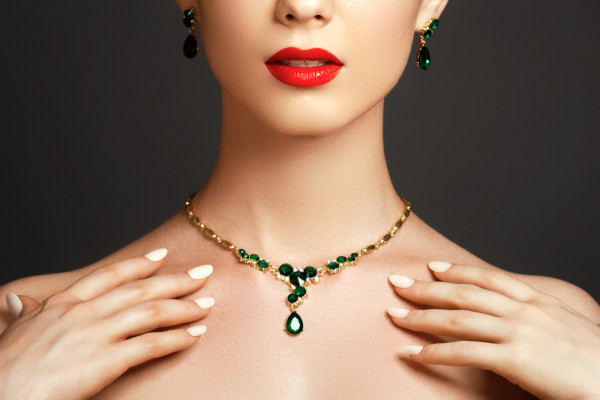 Woman wearing gold necklace for ladies with emerald. Find colourful necklaces at BAUNAT