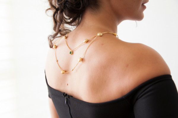 Woman wears gold necklace for ladies on the back. Find gold necklaces at BAUNAT
