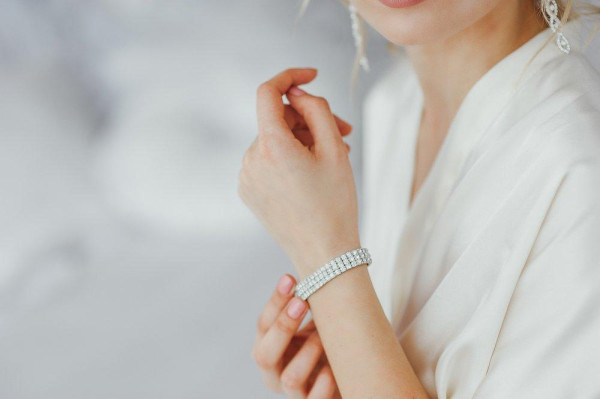 woman being gifted tennis bracelet - White gold tennis bracelet on a blonde woman's wrist. - BAUNAT