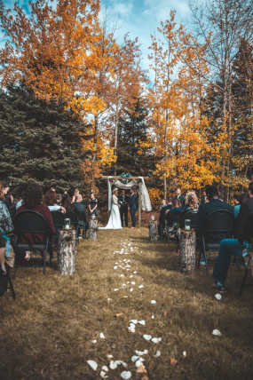 A beautiful autumn wedding ceremony surrounded by colourful fall leaves and warm sunlight filtering through the trees.