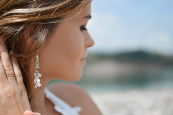 a woman wearing stunning earrings in white gold decorated with pearls as a wedding anniversary gift