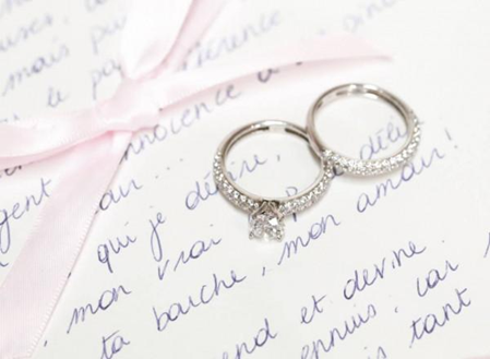 two diamond engagement rings, displayed on a love note