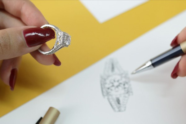 A woman holding a ring while drawing a design