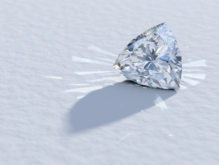 A trillion cut diamond glistens on a pristine white surface, showcasing its brilliance and intricate facets.