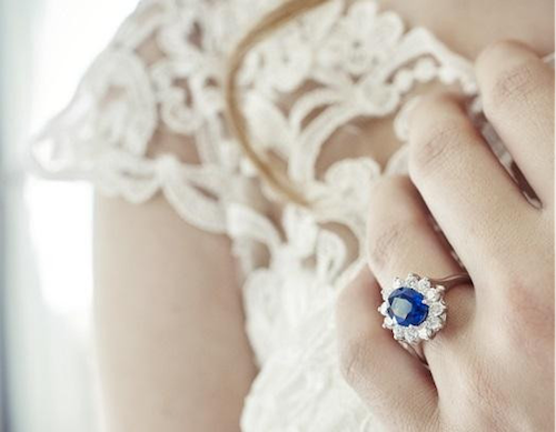 a woman proudly shows off her wedding ring with a stunning blue sapphire for which she paid a high price