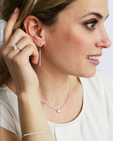 Donna con gioielli in platino BAUNAT, ipoallergenici rispetto all'oro bianco. - Una donna in camicia bianca che indossa gioielli in oro bianco, elegante e sicura di sé.