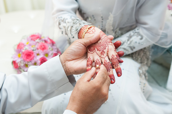 Sposo nella tradizione islamica che infila l'anello di diamanti della sposa al dito anulare destro decorato della mano destra.