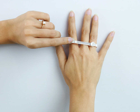 Una donna misura la misura del suo anello tenendo in mano un anello e un coltello, mostrando un approccio unico alla prova dei gioielli.