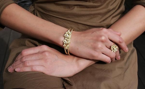Immagine di una donna che mostra uno splendido bracciale in oro adornato con diamanti e un anello abbinato.