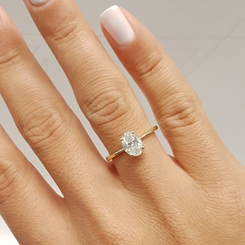 donna che indossa un anello di fidanzamento con diamanti e smalto rosa pallido, che fa risaltare l'anello
