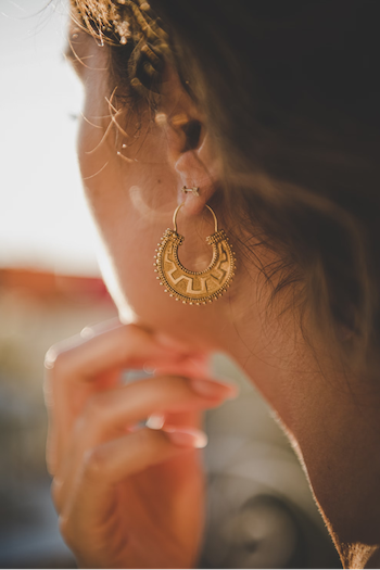 a woman with a striking gold hoop earring, representing the elegance of traditional Greek jewellery.