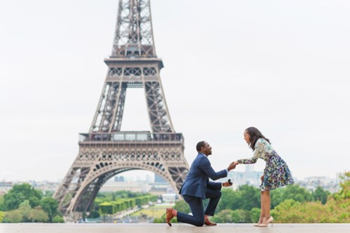 a man bending the knee in front of the Eiffel Tower, a famous place for marriage proposals in Paris