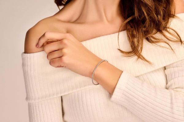 A woman with long hair wearing a stylish combination bracelet on her wrist, showcasing her unique fashion sense.