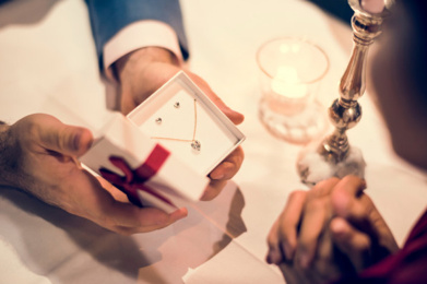 A man gives a woman jewelry. Find the perfect wedding anniversary jewelry at BAUNAT