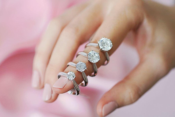 a woman wearing multiple solitaire diamond rings on her index finger, showcasing a desire to rule