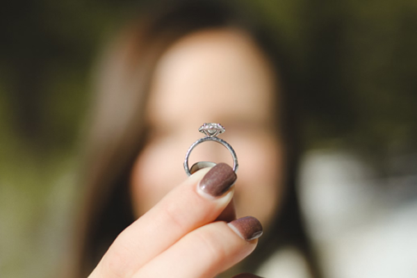 woman holding a pink solitaire diamond engagement ring with a silver band