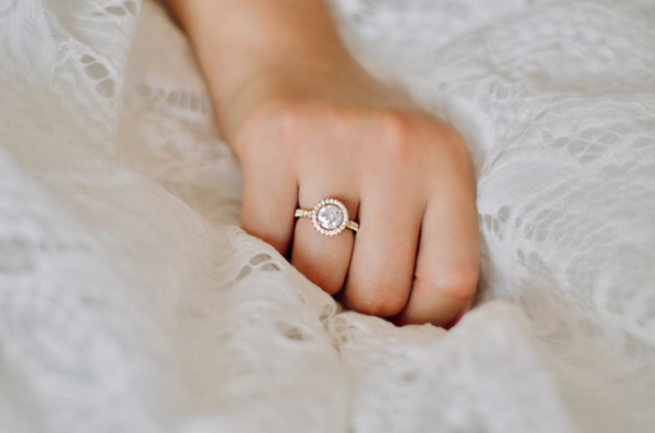 A woman's hand delicately presents a beautiful diamond ring, highlighting the convenience of purchasing engagement rings online