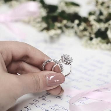 woman's hand holding two diamond rings, each having a different carat weight