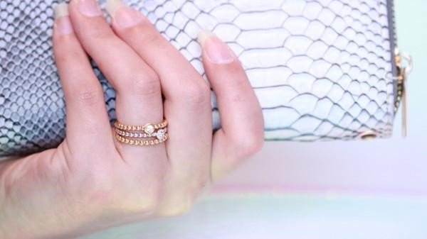 woman's hand holding snake skin purse, wearing rings with different precious metals and carat weights