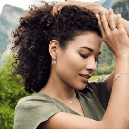 a woman with curly hair, elegantly accessorised with earrings from the monarca collection